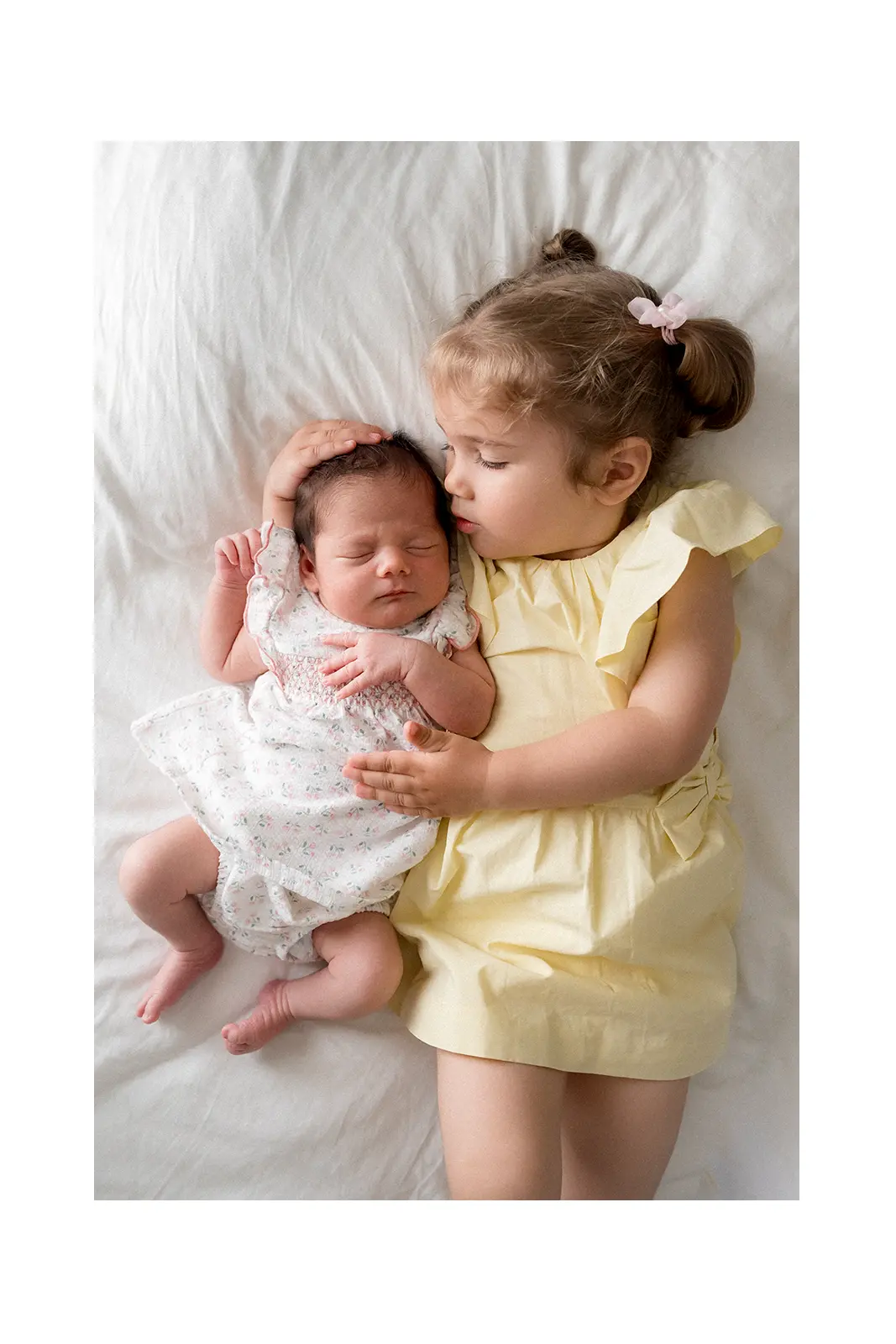 Starija seka ljubi novorođenu bebu na krevetu