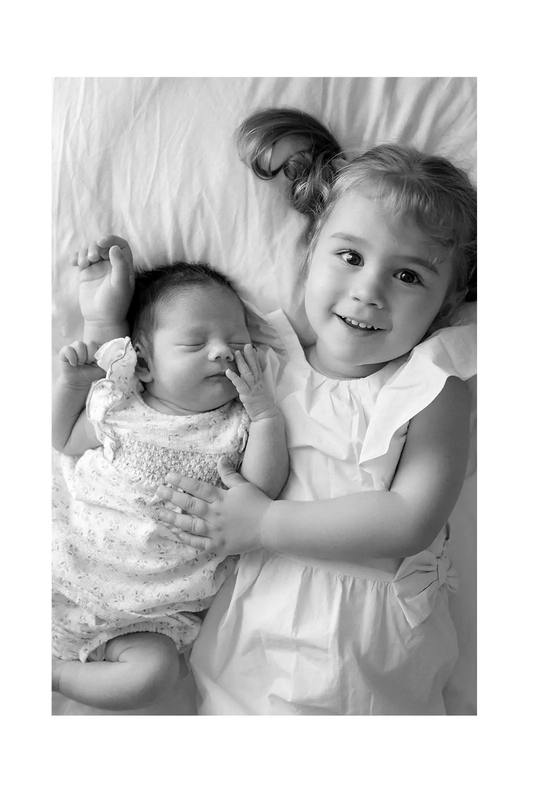 Beba i starija sestra zagrljene na krevetu