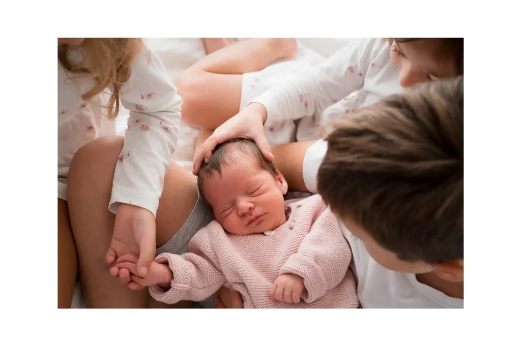 Starija djeca drže malu bebu u krilu.