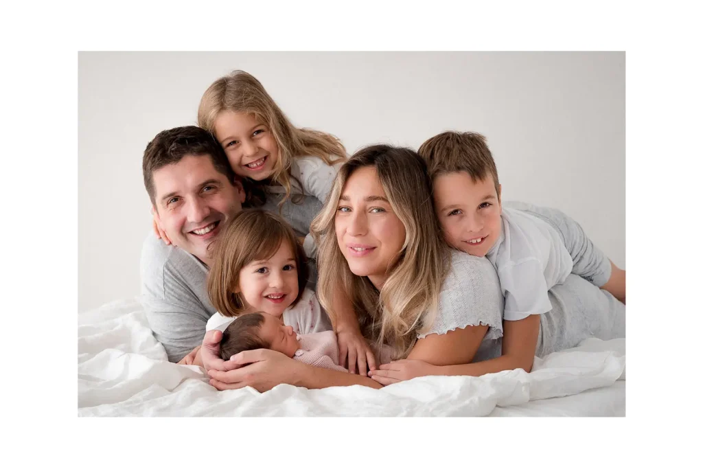 obitelj pozira na krevetu s novorođenom bebom