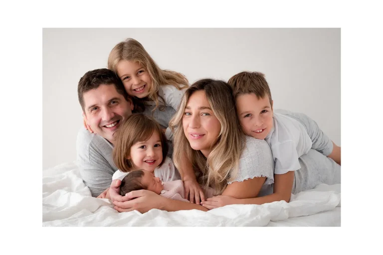 obitelj pozira na krevetu s novorođenom bebom